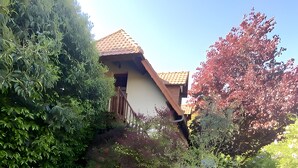 A patio with a table and chairs, surrounded by lush greenery and a house with a tiled roof. - Bed and Breakfast 'Sous Les Bruyères' with Private Terrace, Private Garden and Wi-Fi (Sainte-Marguerite-sur-Mer)