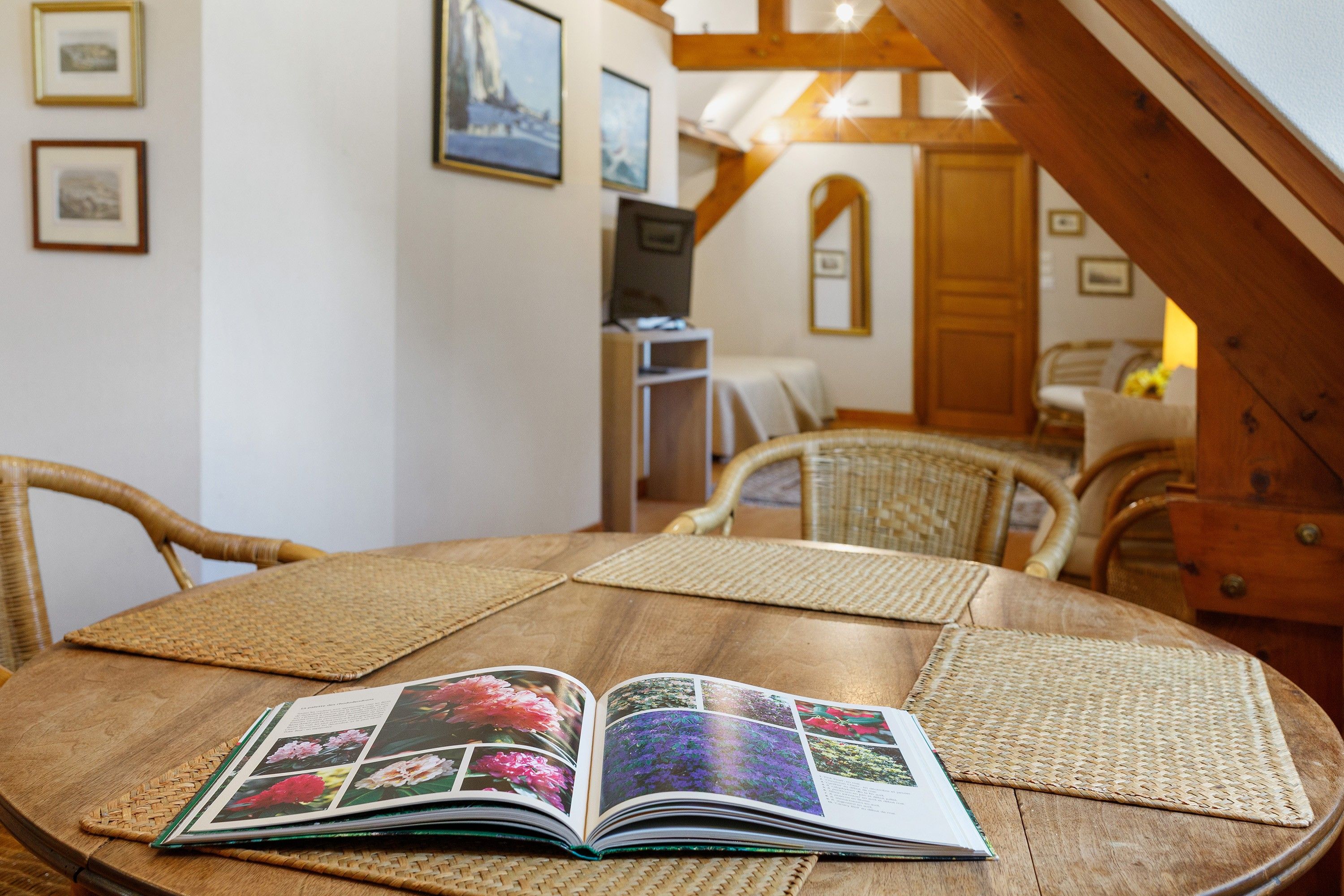 Une table ronde en bois sur laquelle est posé un album photo ouvert, présentant différentes sortes de fleurs.