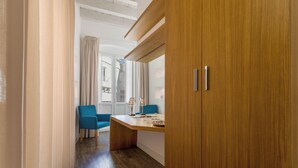 A hotel room with a wooden wardrobe, a desk with a lamp, and a blue chair. - Star Suite Superior by BarbarHouse (Taranto)