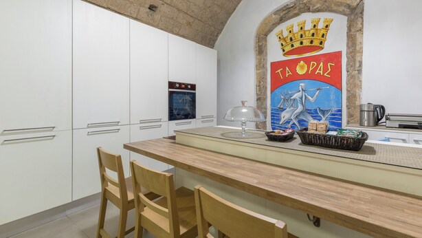 A kitchen with a central island, white cabinets, and a decorative archway with a coat of arms. - Star Suite Superior by BarbarHouse (Taranto)