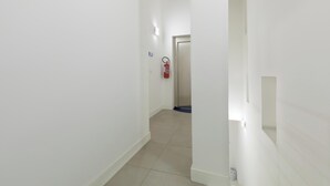 A narrow hallway with white walls and a tiled floor. A fire extinguisher is mounted on the wall. - Star Suite Superior by BarbarHouse (Taranto)