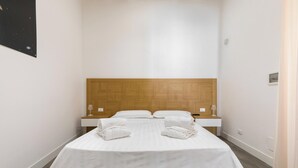 A hotel room with a wooden headboard, a bed with white linens, two bedside tables, and a nightstand. - Star Suite Superior by BarbarHouse (Taranto)