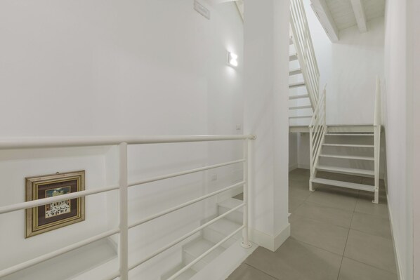 A staircase with white railings and a framed picture on the wall.