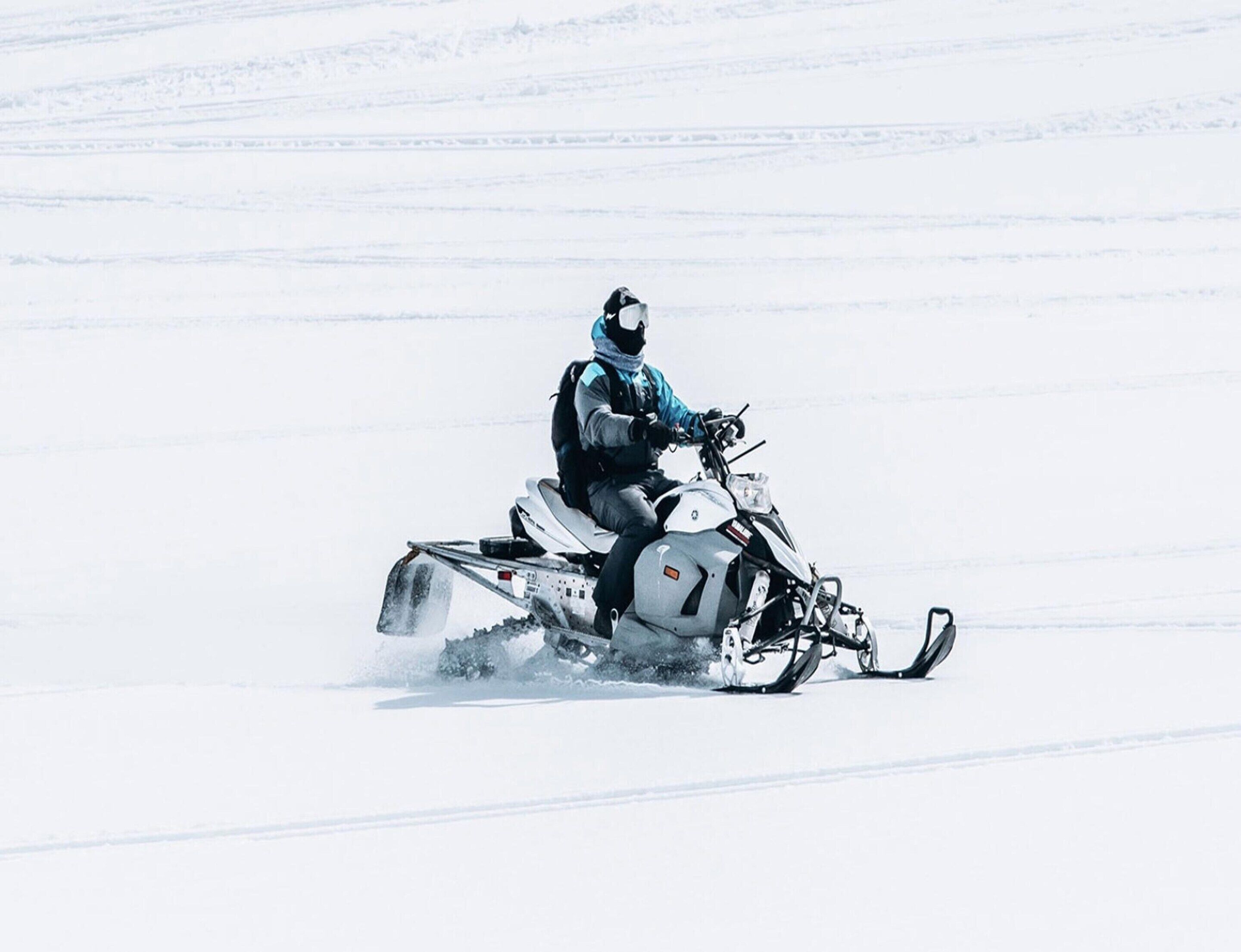 Ein Schneemobilfahrer in einer verschneiten Landschaft.