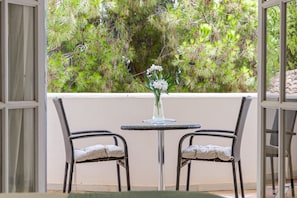 An outdoor seating area with two wicker chairs and a small round table, featuring a vase with white flowers.