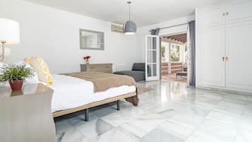 Un dormitorio con cama, mesita de noche, lámpara, cómoda, espejo y vistas a un patio exterior.