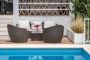 A poolside seating area with wicker furniture and a white wall with a lattice design. - Villa Alegre - Charming Villa With Private Pool (Benahavis)