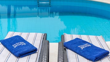 A swimming pool with two lounge chairs and towels.