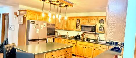 A modern kitchen with wooden cabinets, stainless steel appliances, and a bar area.
