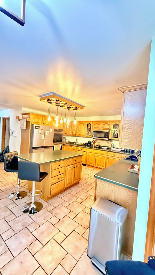 A modern kitchen with wooden cabinets, stainless steel appliances, and a bar area.
