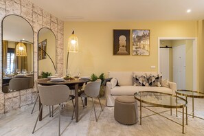 Ein modernes Wohnzimmer mit Essbereich, ausgestattet mit einer Couch, Stühlen, einem Couchtisch und einem für eine Mahlzeit gedeckten Esstisch.