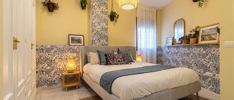 A bedroom with a bed, bedside lamps, a hanging light fixture, and wall-mounted plants.