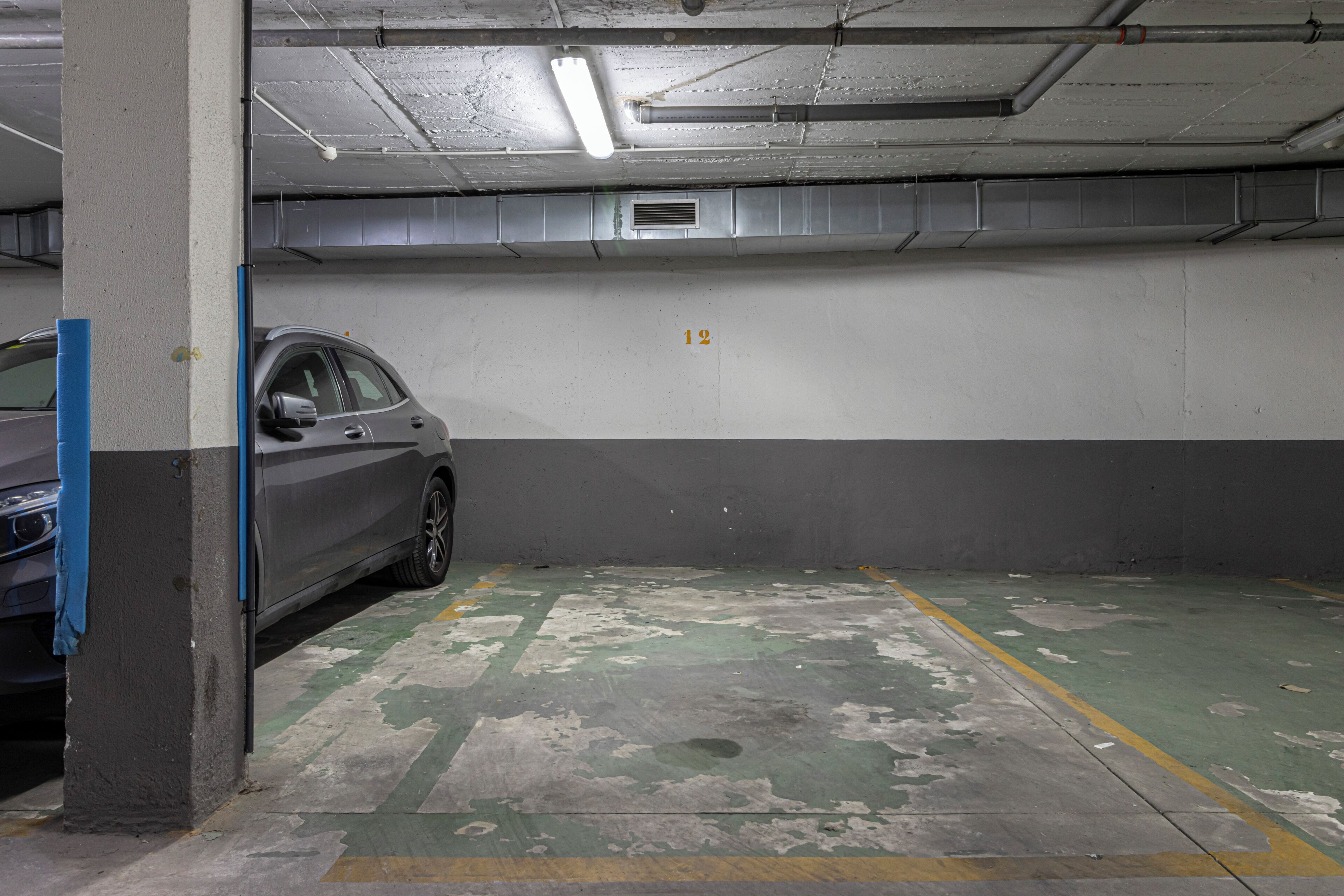 A parking garage with a car parked in a space marked with the number 12.