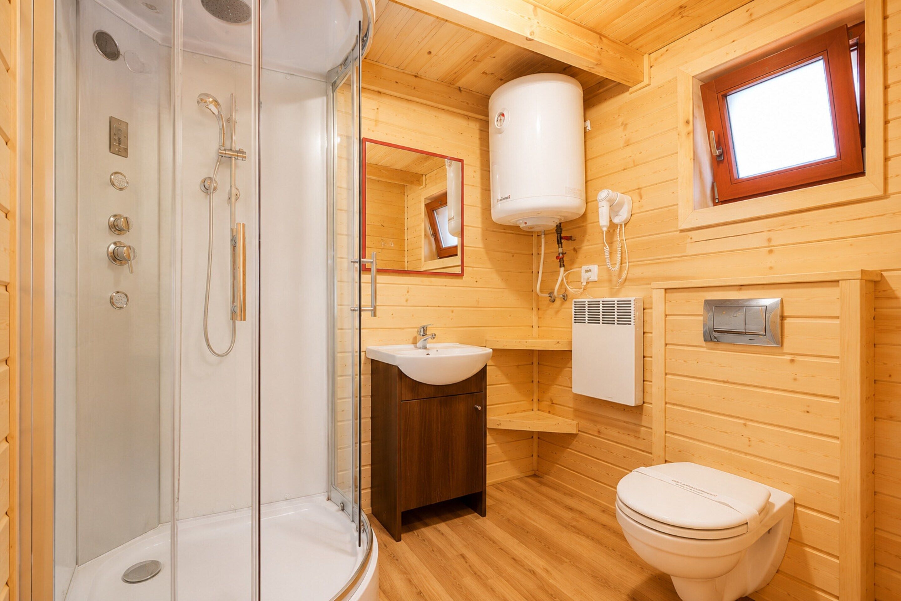 A compact bathroom with a glass-enclosed shower, a sink, a toilet, and a mirror.