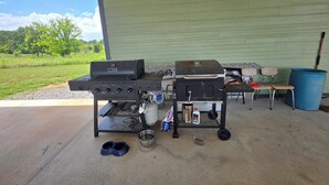 En udendørs grillopsætning med grill, gasflaske og et bord med en stol.
