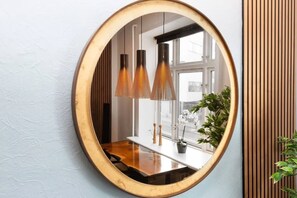 A mirror with an oval frame, a wooden table, and two pendant lights.