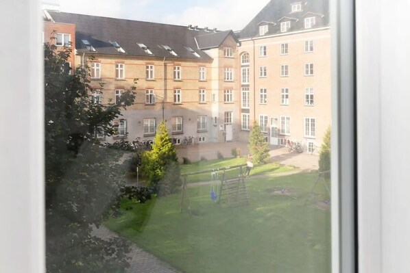 A courtyard with a playground, surrounded by multi-story buildings with windows and balconies.