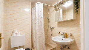 A bathroom with a toilet, sink, shower, and a mirror. - City Studio Koblenz Central (Koblenz)