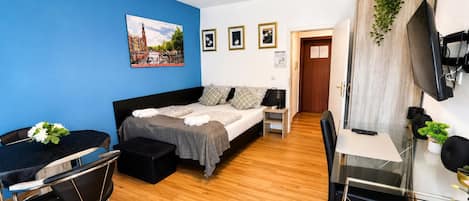 Habitación de hotel con cama, escritorio, silla, televisión y un cuadro en la pared.