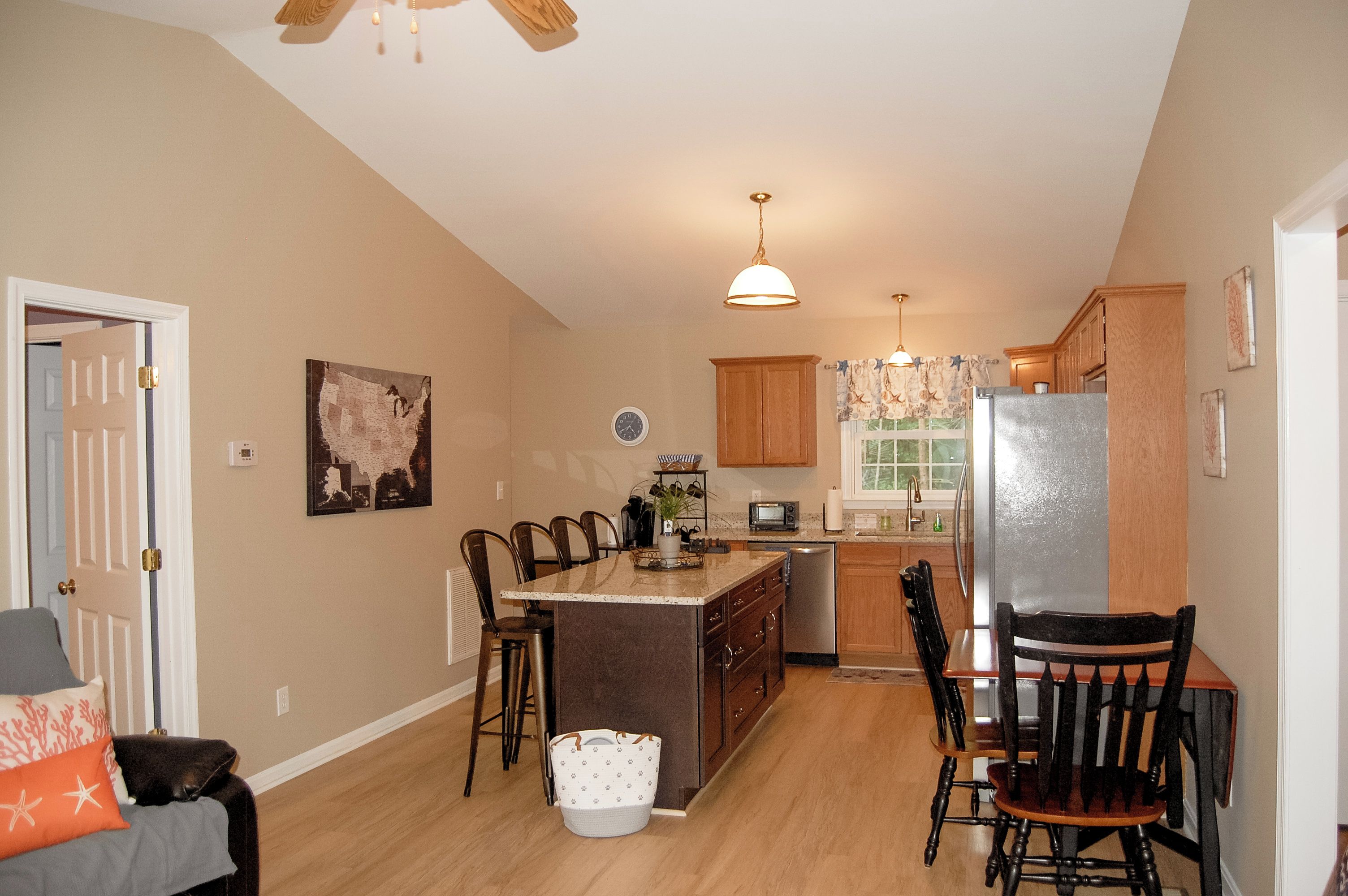 A kitchen with wooden cabinets, a central island, and a dining area with chairs.