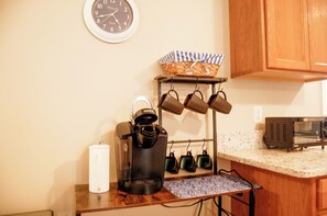 Una cucina con orologio, bollitore, tostapane e macchina del caffè su un piano di lavoro.