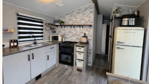 Una cocina con armarios blancos, microondas, estufa y refrigerador.