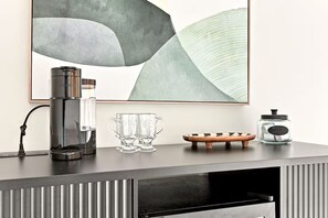 Eine moderne Küche mit einer Kaffeemaschine, zwei Gläsern, einer Holzschale und einem Glas auf der Arbeitsfläche.