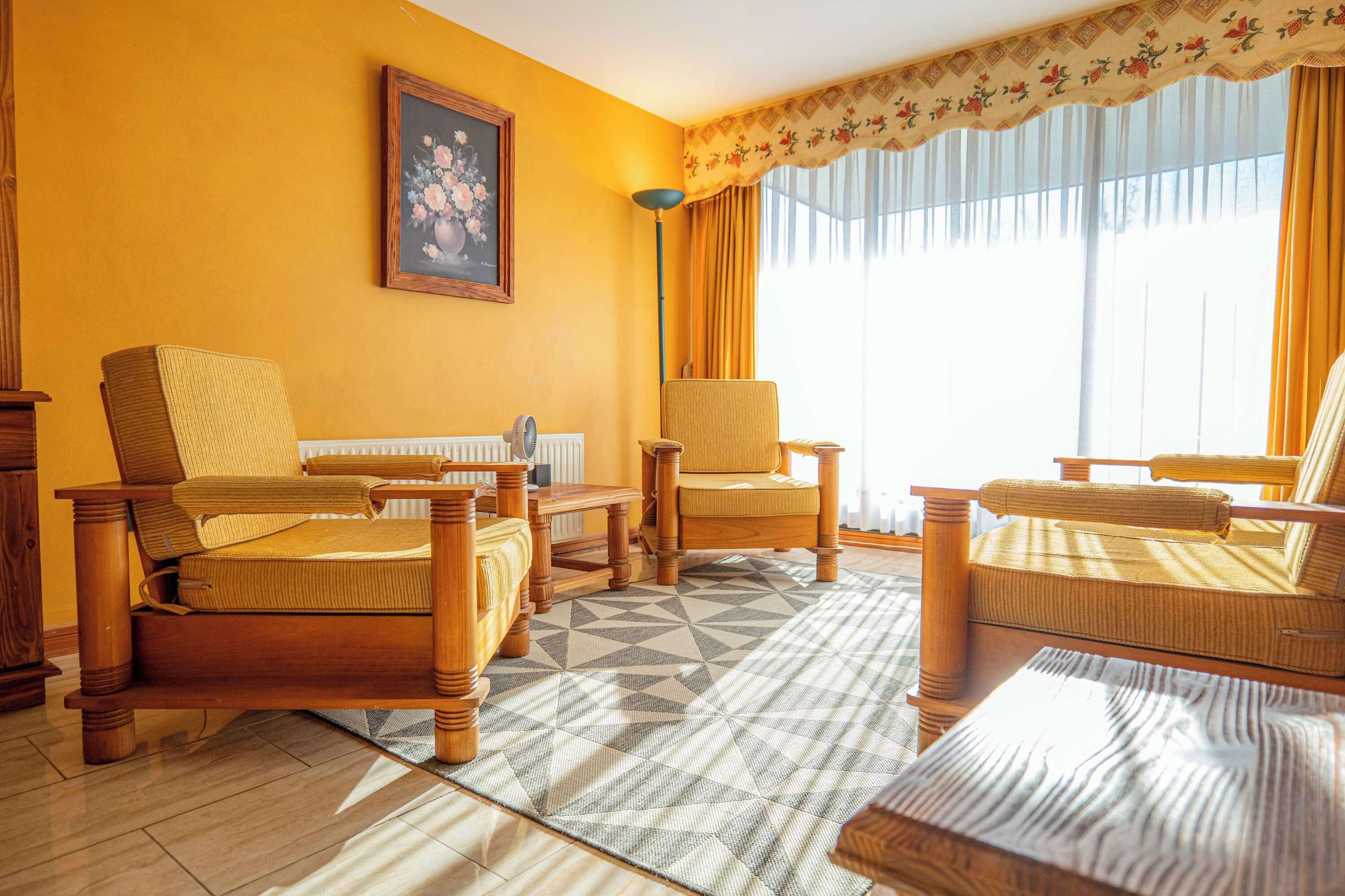 A living room with wooden furniture, a patterned rug, and a painting on the wall.