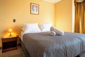 Ein Hotelzimmer mit einem Bett, einem Nachttisch mit Lampe und einem Bild an der Wand.