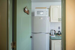 A compact kitchen with a white refrigerator, a microwave, and a coffee maker on the counter. - Vive Pucón: 3D/2B, Balcón y Estacionamiento (Pucon)