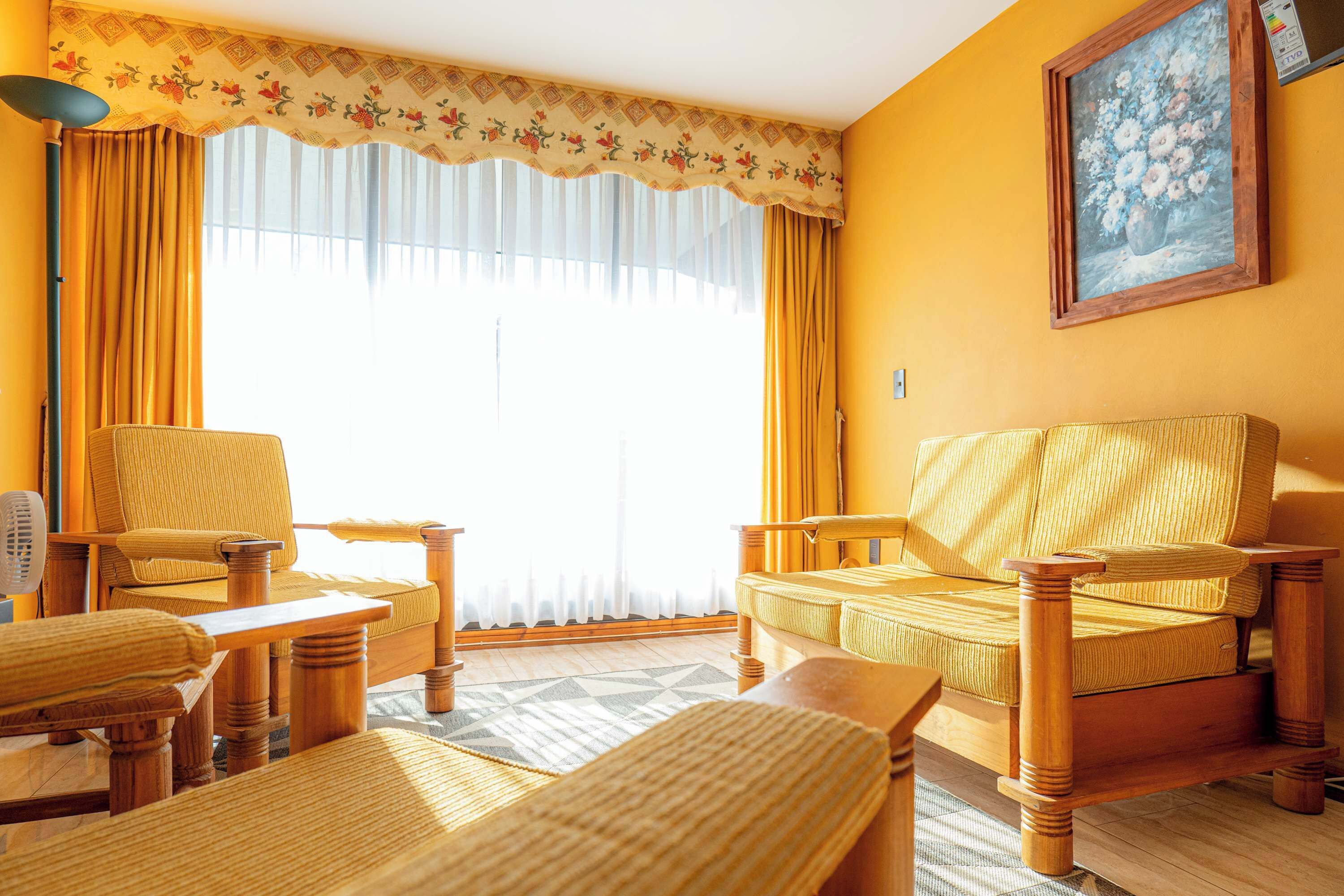 Ein Zimmer mit einer Couch, zwei Sesseln, einem Tisch und einem Bild an der Wand.
