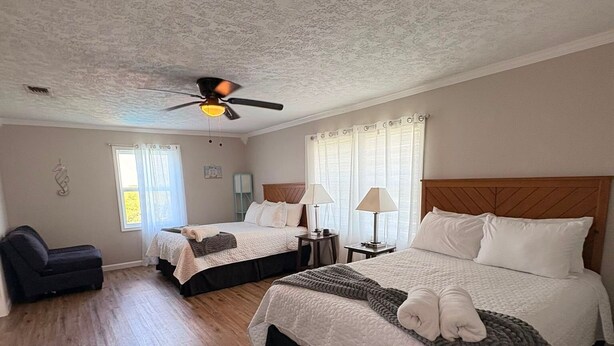 Ein Hotelzimmer mit zwei Betten, einem Deckenventilator, einer Couch und einem Fenster mit Vorhängen.