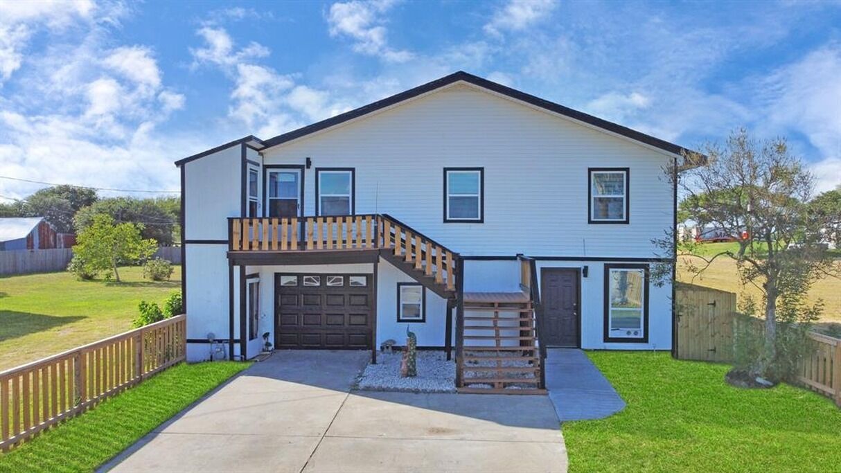 A two-story house with a front porch, a garage, and a small front yard.