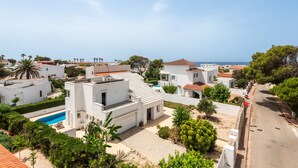 A residential area with modern white buildings, a swimming pool, and a clear view of the sea.