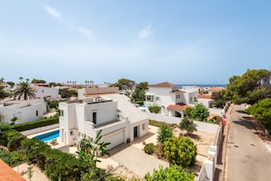 A residential area with modern white buildings, a swimming pool, and a clear view of the sea. - Magdalena 3 bedroom villa, Cala Blanca (Cala Blanca)