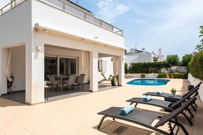 Ein moderner Poolbereich im Freien mit Liegestühlen und einer überdachten Sitzgelegenheit.