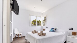 A modern bedroom with a bed, a chair, a nightstand, and a television.