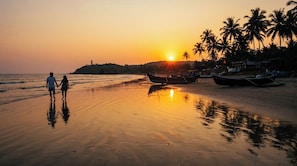 Eine Strandansicht mit Sonnenuntergang, Palmen und Booten.
