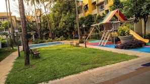 A courtyard with a playground, a bench, and a pool. - Vibe o1: Boutique 2BHK w/pool | Just 2 mins drive to Anjuna Beach (Anjuna)