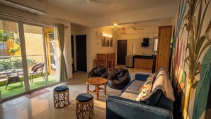 A modern living room with a sofa, coffee table, and chairs, a dining area with a table and chairs, and a kitchen in the background. - Vibe o1: Boutique 2BHK w/pool | Just 2 mins drive to Anjuna Beach (Anjuna)