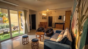 Ein modernes Wohnzimmer mit Sofa, Couchtisch und Sesseln, ein Essbereich mit Tisch und Stühlen sowie eine Küche im Hintergrund.