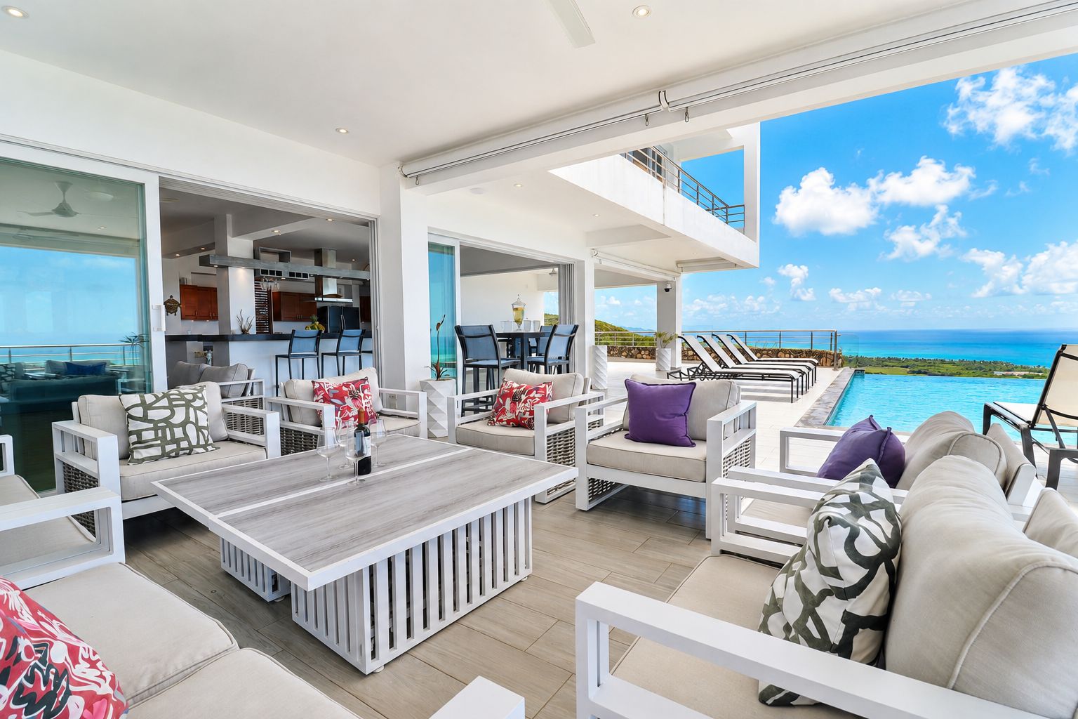 A modern outdoor living space with a pool, seating areas, and a view of the ocean.
