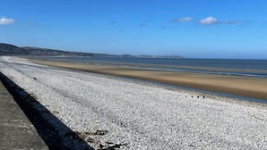 A pebble beach with a clear sky and distant hills. - Golden Sands 8 Berth Cosy Caravan (Rhyl)
