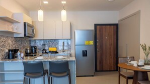 A modern kitchen with a marble countertop, stainless steel appliances, and a wooden dining table with chairs. - Furnished 2 Bedroom Apartment in Panama (Panamá)