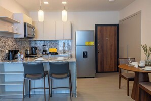 Una cocina moderna con encimera de mármol, electrodomésticos de acero inoxidable y una mesa de comedor de madera con sillas.