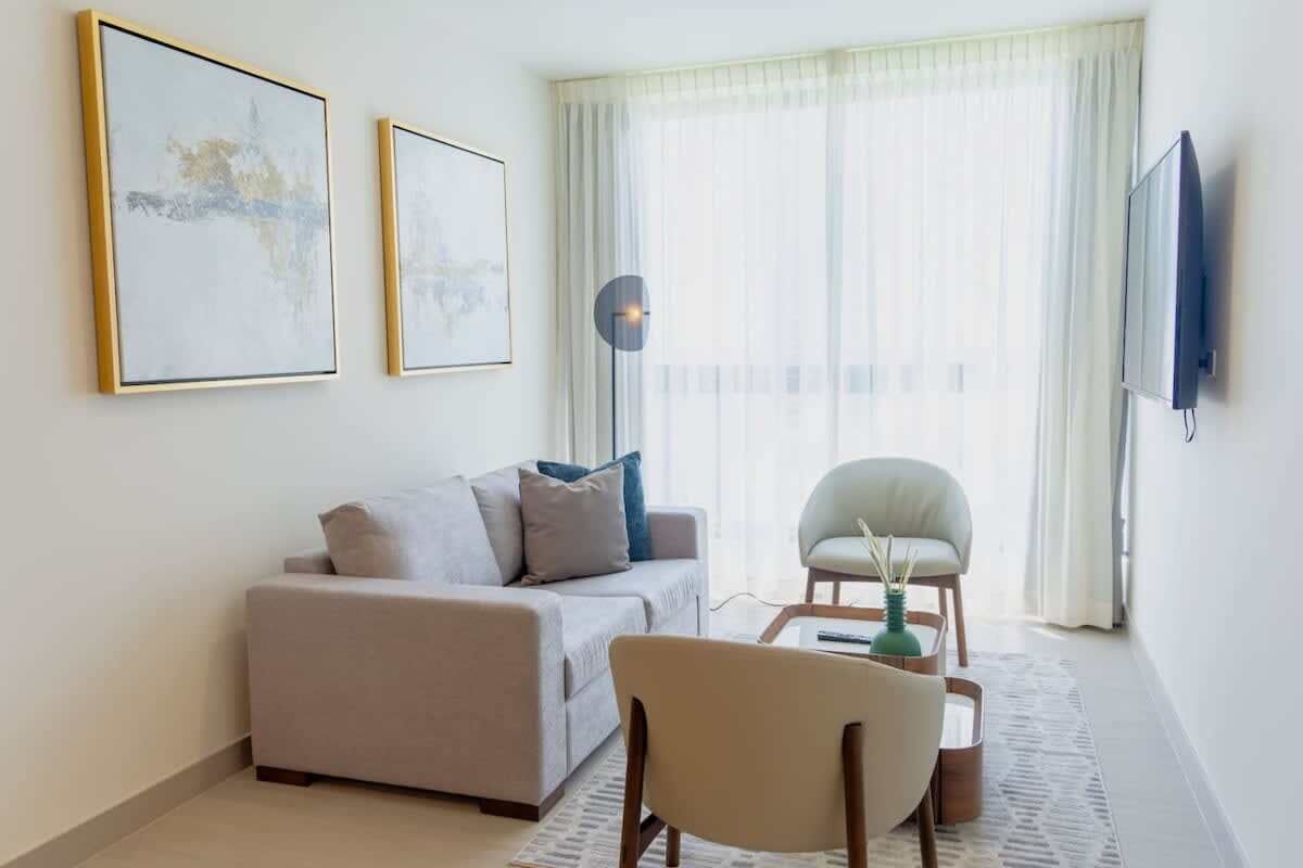 Una sala moderna con sofá, sillón, mesa de centro y una obra de arte en la pared.