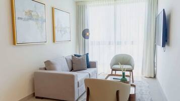 Una sala moderna con sofá, sillón, mesa de centro y una obra de arte en la pared.