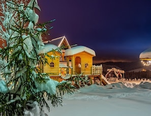 A wooden cabin with a snow-covered roof, surrounded by snow-covered ground and trees. - Highland-style Holiday Home, Sauna, Jacuzzi (Poronin)