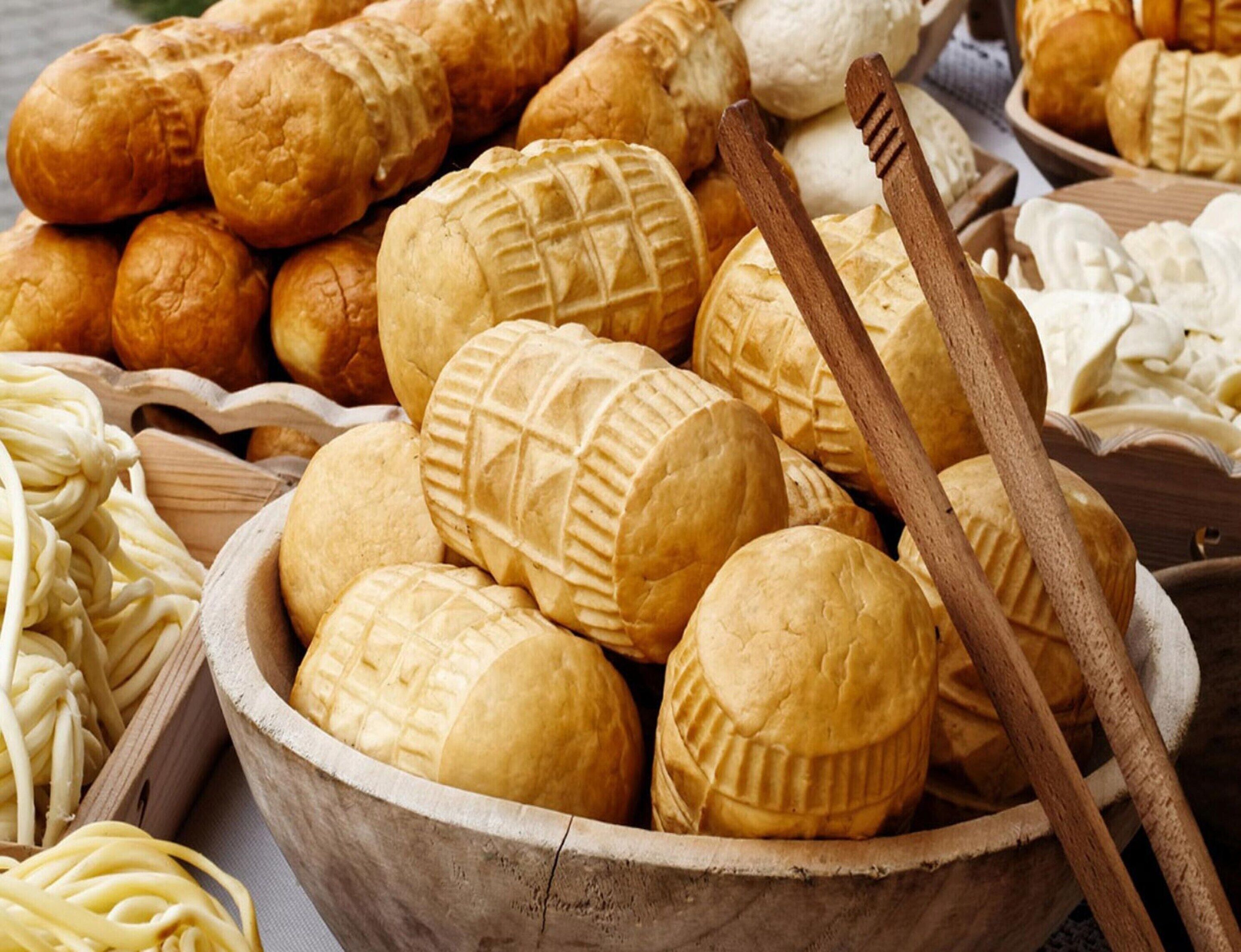 Une variété de produits de boulangerie, notamment du pain, des petits pains et des pâtisseries, présentés dans un saladier en bois.