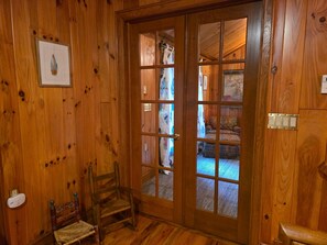A wooden interior with a door leading to a room with patterned upholstery and a small rug. - Judges Hilltop - Highlands, NC (Highlands)